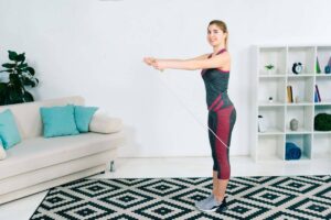 Woman exercising with resistance band in a bright, minimalist living room.