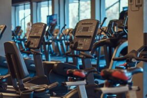 A gym interior featuring several stationary bikes and treadmills arranged for fitness activities.