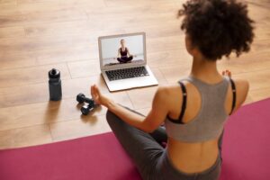Woman practising yoga at home following an online class on her laptop.