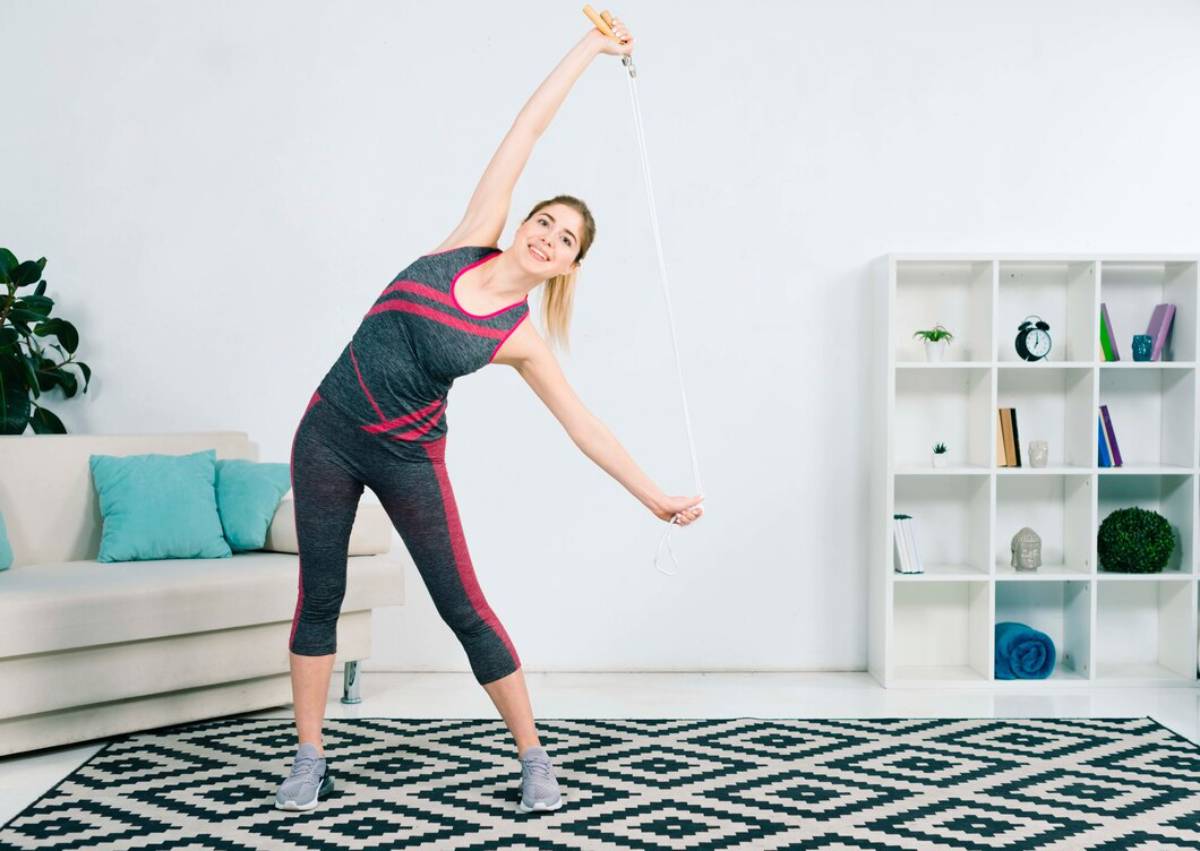 Woman stretching with a jump rope in a bright home living room. 