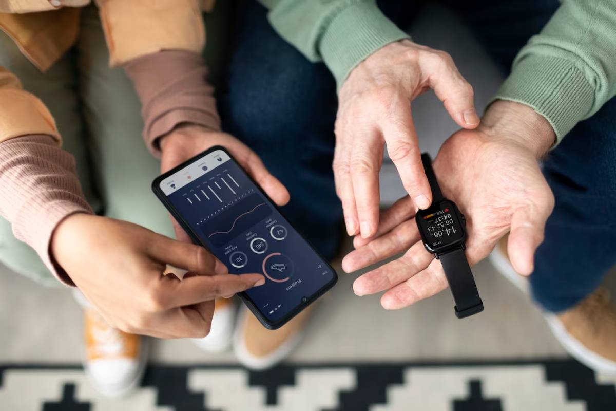 Two people sitting, comparing health data on a smartphone and smartwatch. 