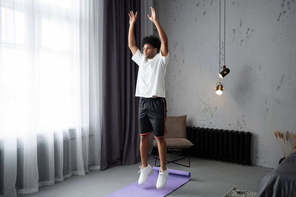 Young man stretching arms above his head on a yoga mat in a modern room.