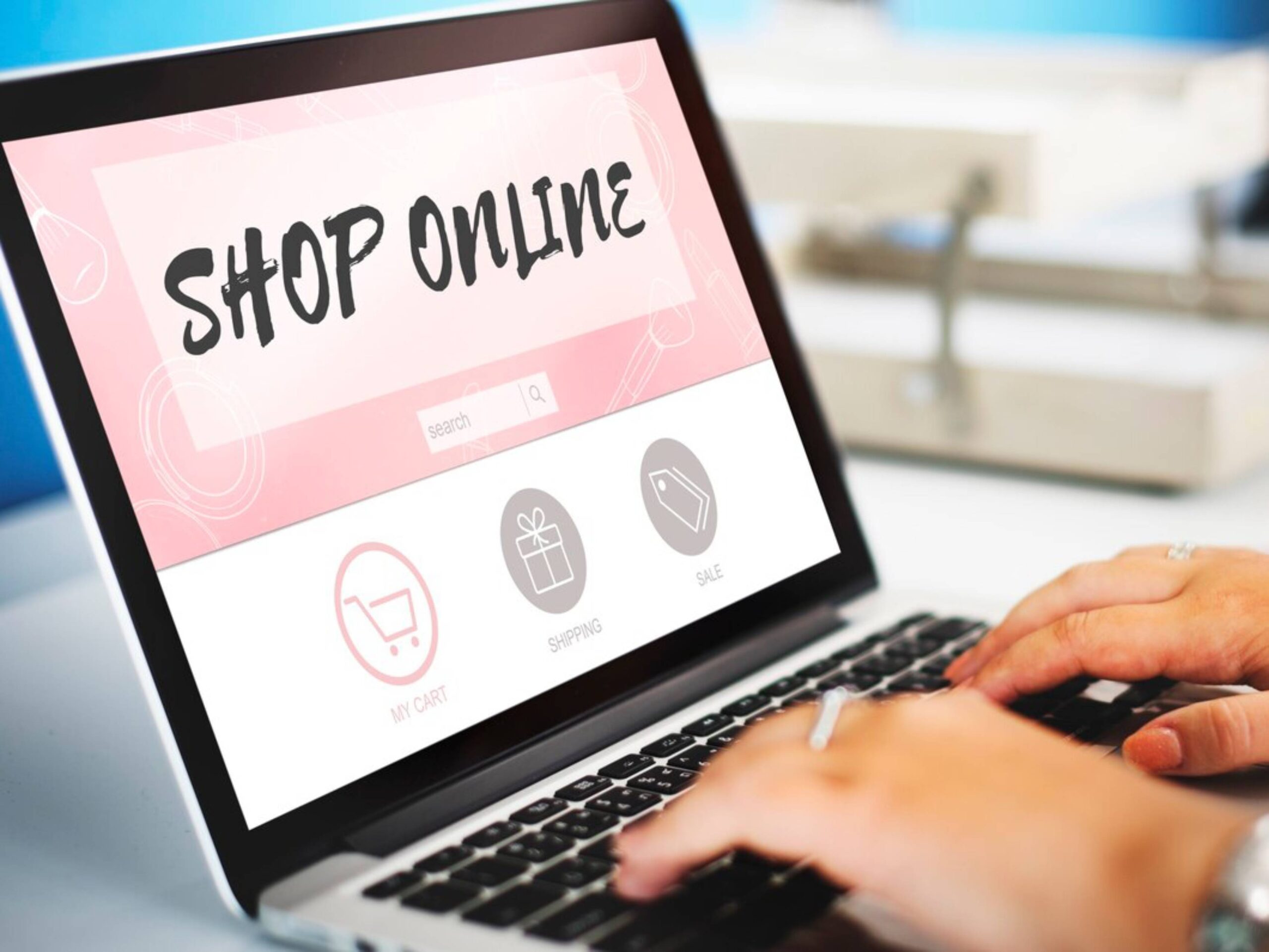 Person shopping online on a laptop displaying a shop online screen with shopping cart and sale icons.