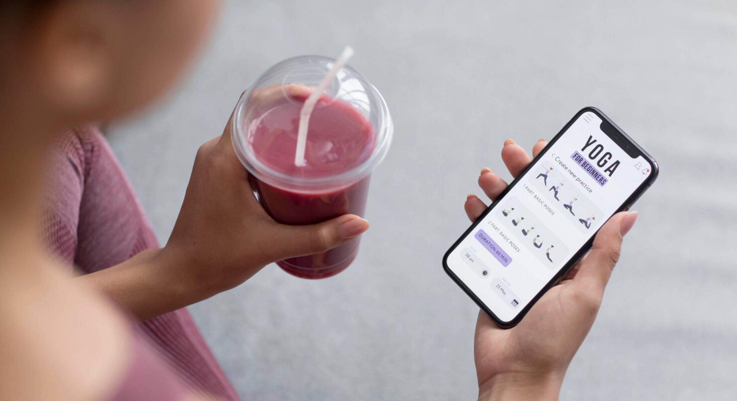  Woman holding a smoothie and viewing a yoga app on her smartphone.