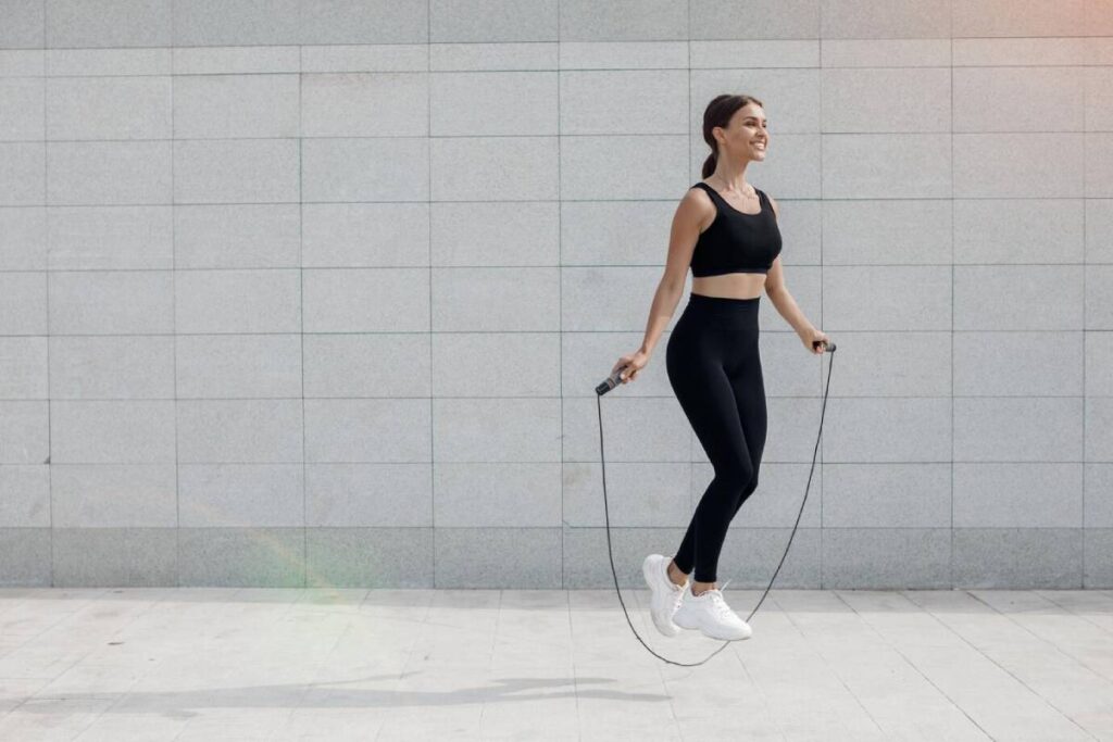 A woman in black leggings and a sports bra jumps rope, showcasing her athleticism and fitness routine.