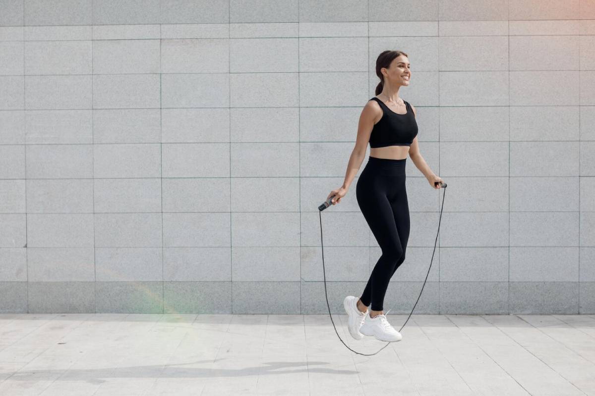 A woman in black leggings and a sports bra jumps rope, showcasing her athleticism and fitness routine.